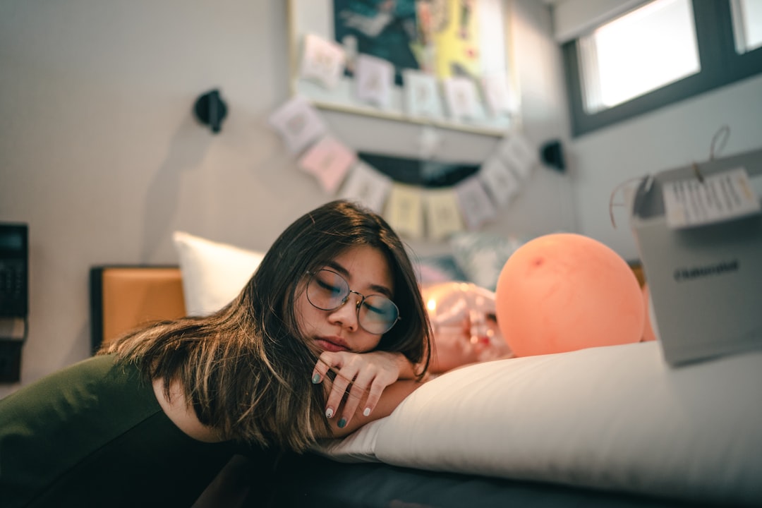 woman in black framed eyeglasses lying on bed