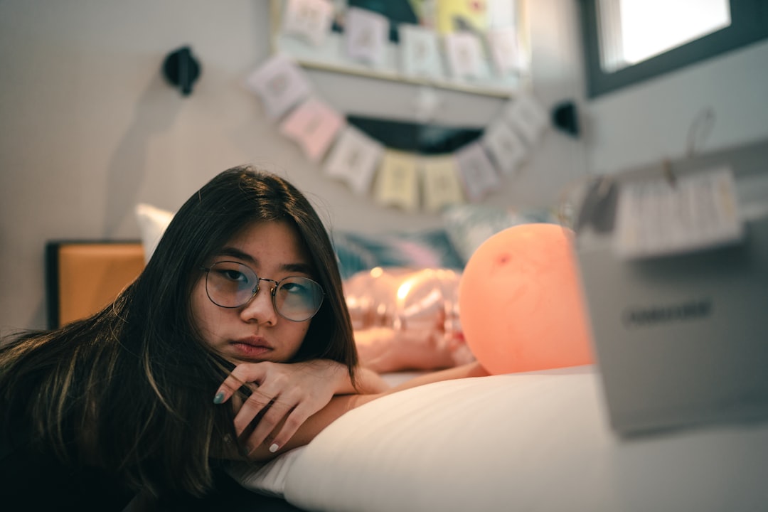 woman in black framed eyeglasses and black long sleeve shirt lying on bed