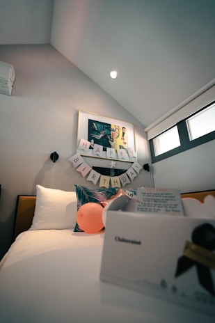 Colorful balloons spelling out 'Happy Birthday' above a decorated bed in a warmly lit room.