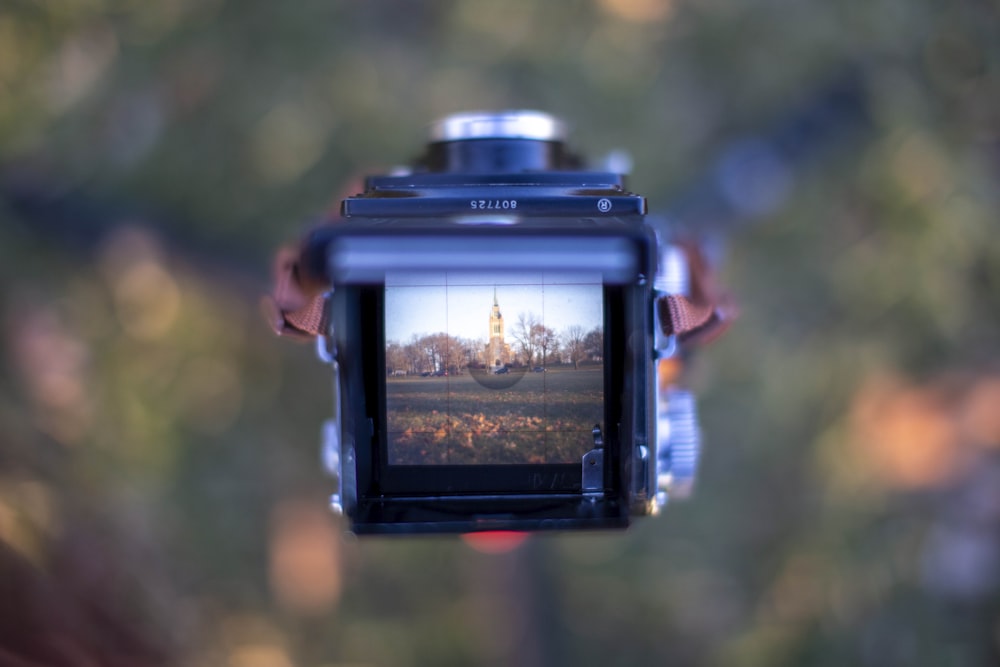 black dslr camera taking photo of brown and green trees during daytime