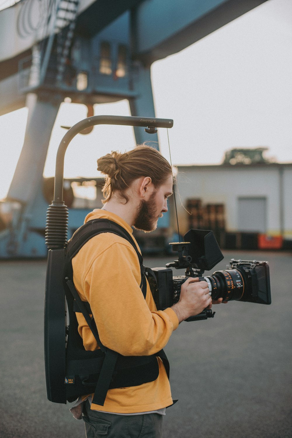 man in brown jacket holding black dslr camera