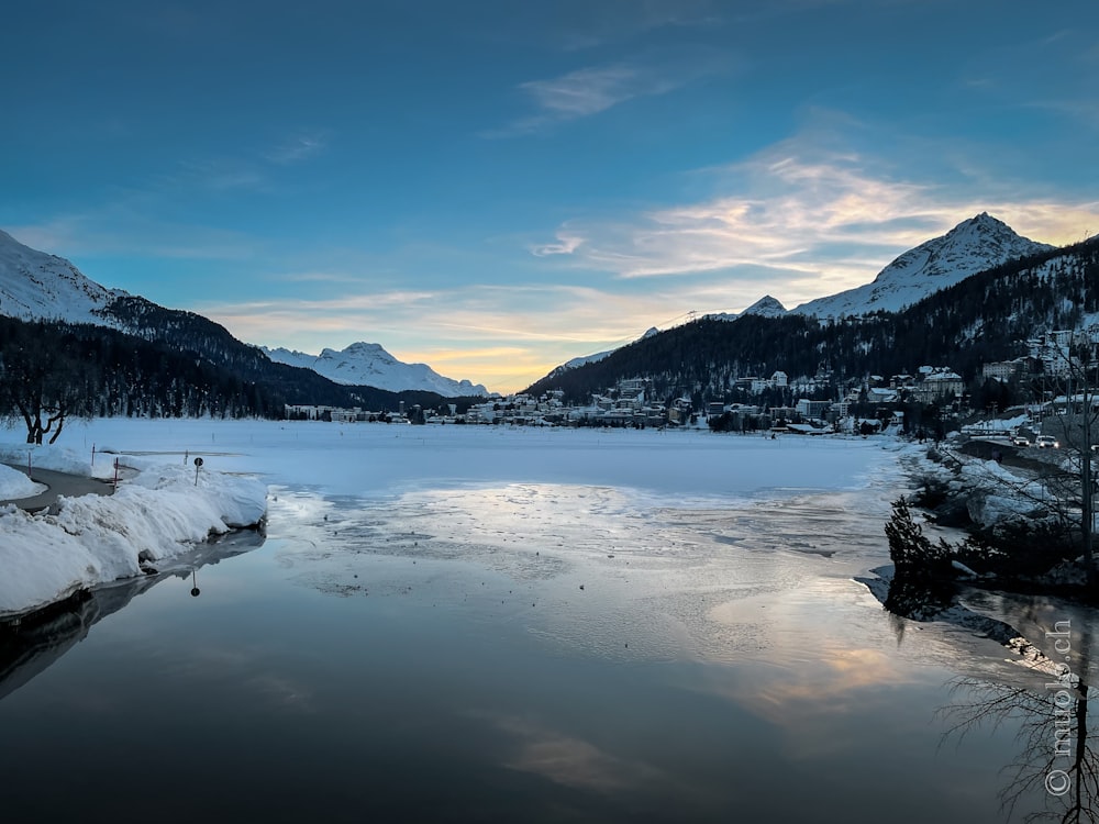 body of water near snow covered mountain during daytime