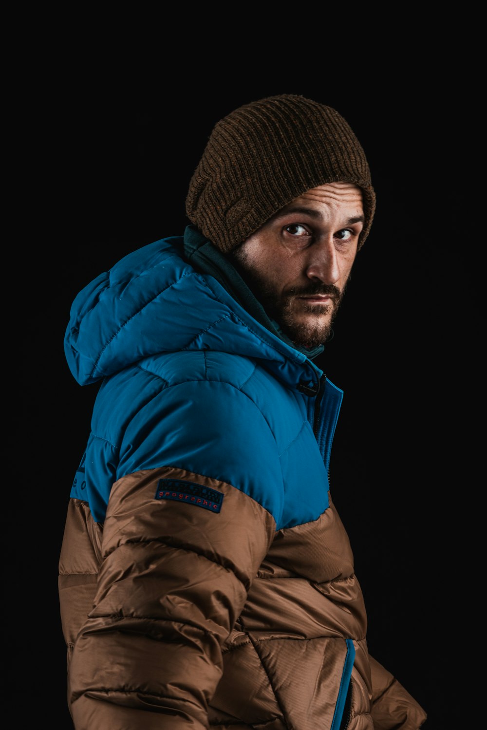 man in blue bubble jacket and brown knit cap