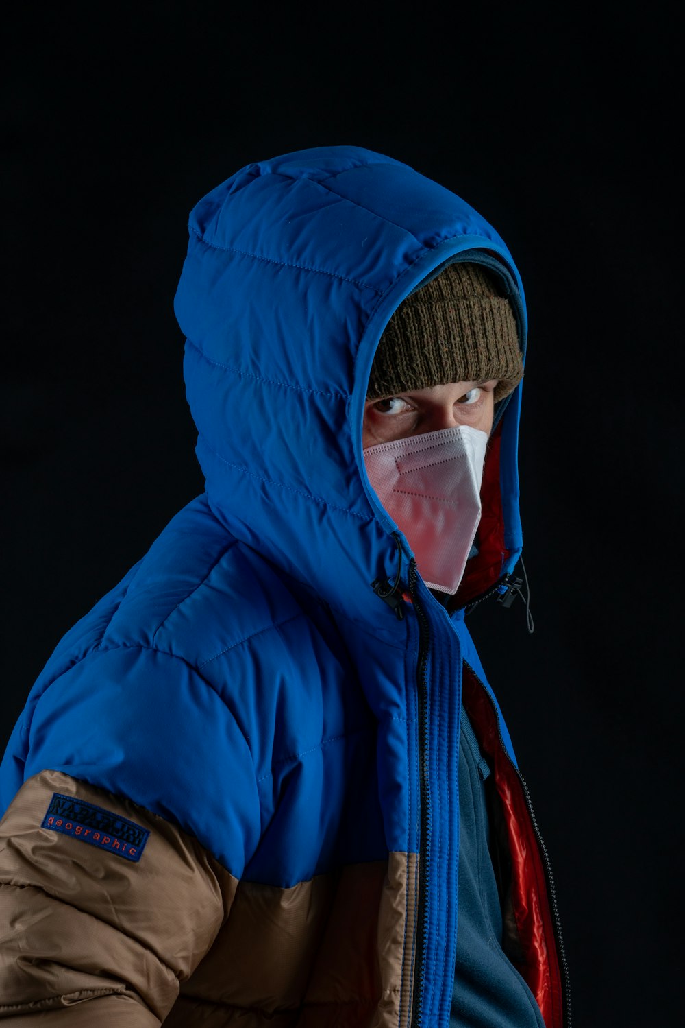 man in blue and black jacket wearing white mask