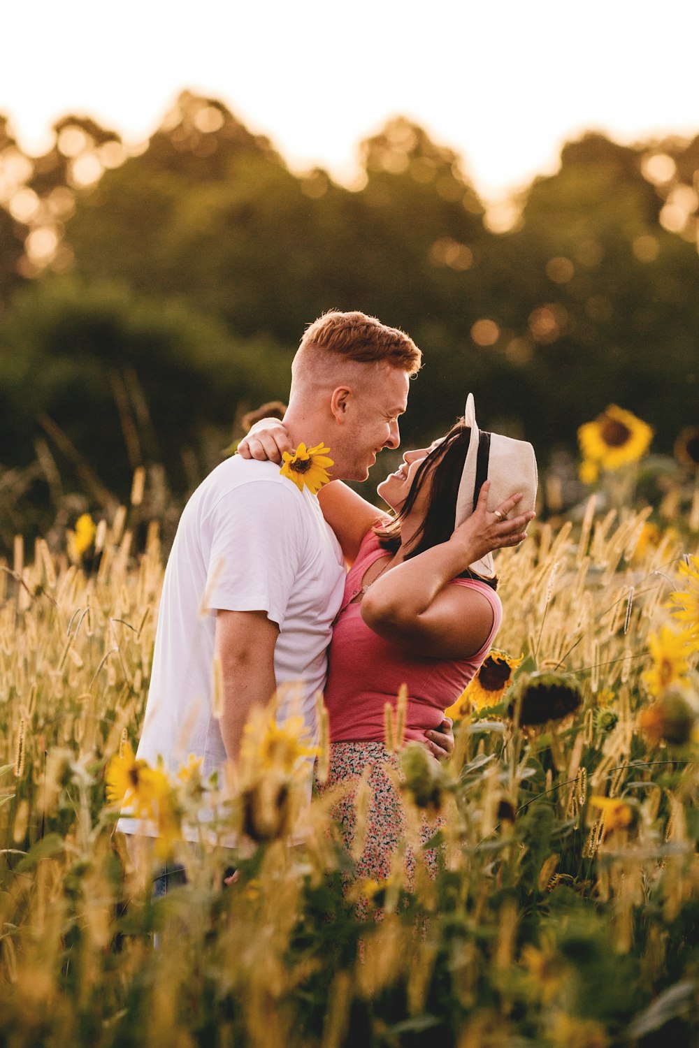 man in white crew neck t-shirt kissing woman in red tank top on green grass