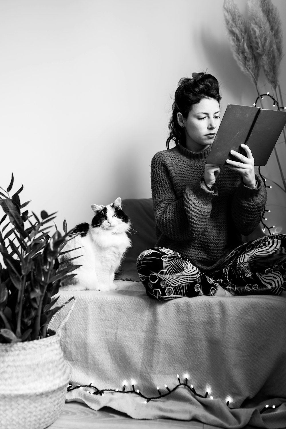 woman in black and white striped long sleeve shirt sitting on couch with cat on lap