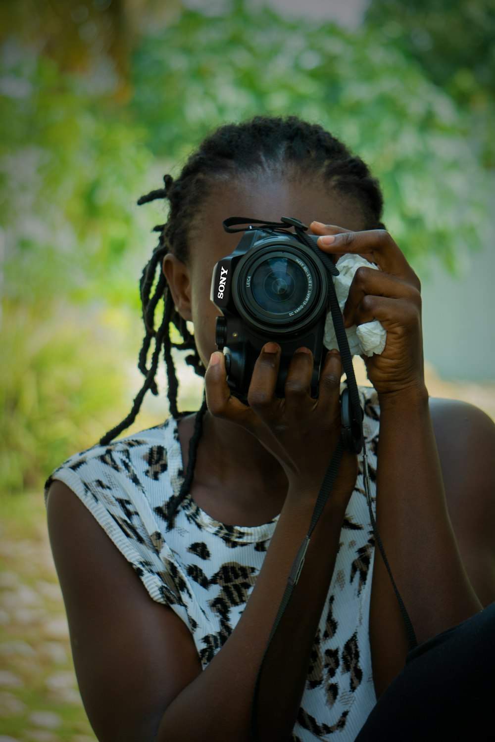 woman in black and white floral tank top holding black nikon dslr camera