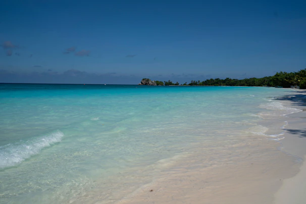 A tranquil beach with crystal-clear turquoise water and soft white sand under a pastel sky