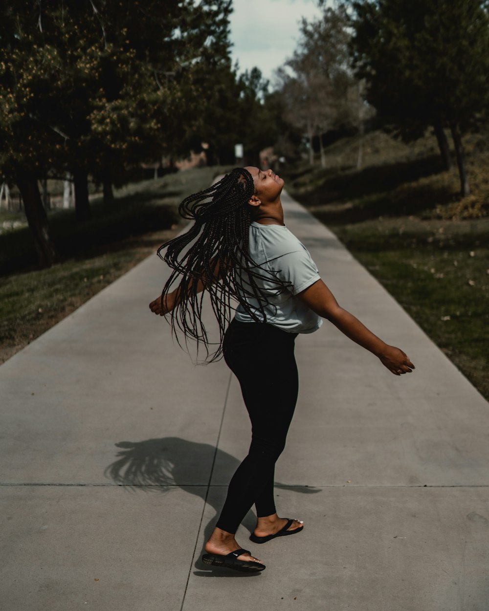 woman in white t-shirt and black pants walking on sidewalk during daytime