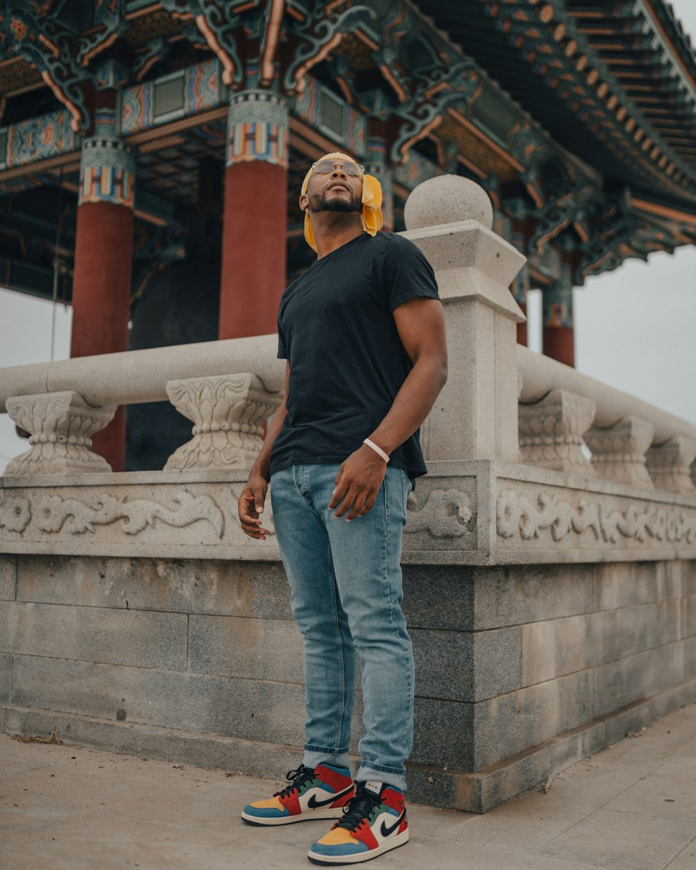 man in black t-shirt and blue denim jeans standing on gray concrete stairs during daytime