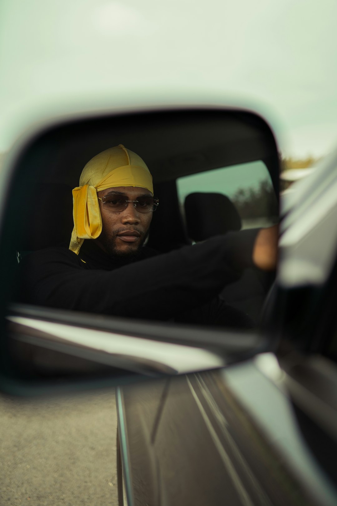 man in black jacket wearing yellow cap sitting on car seat