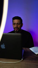 Man working on a laptop with turquoise and purple gradient lighting.