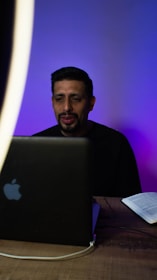 A professional man working on a laptop with PDF files on the screen, blue-themed background.