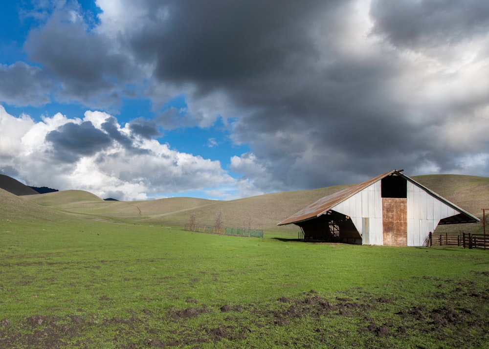 brown wooden barn on green grass field under blue sky and white clouds during daytime