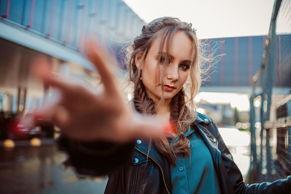 woman in green jacket holding smartphone