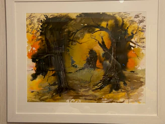 A framed abstract painting with deep forest green and muted clay brushstrokes against a soft charcoal wall.
