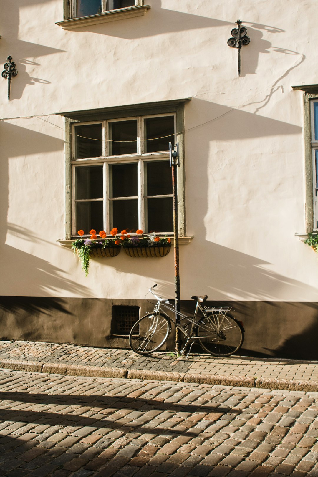 black city bike parked beside white concrete wall