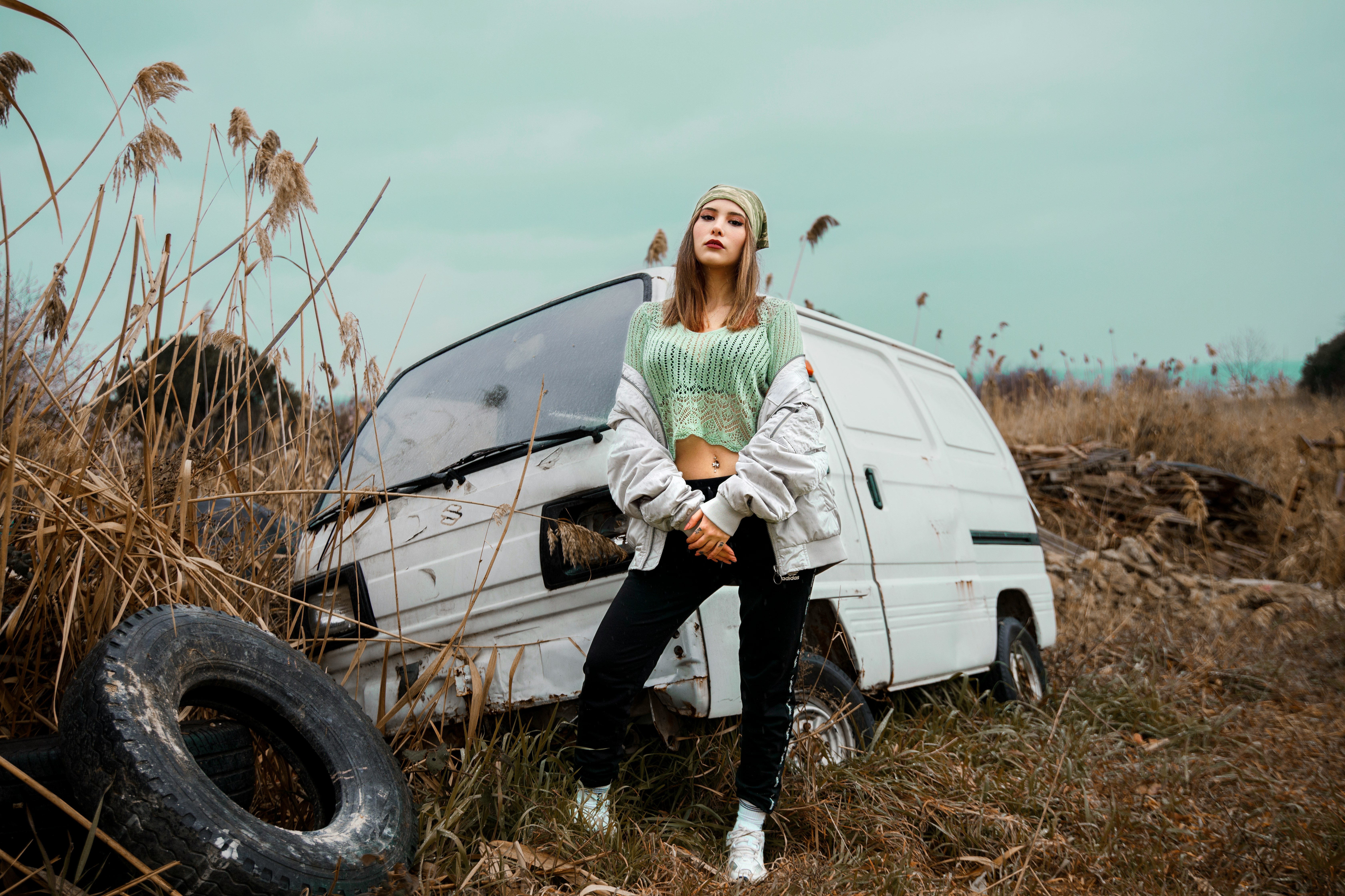 woman in green jacket and black pants standing beside white car