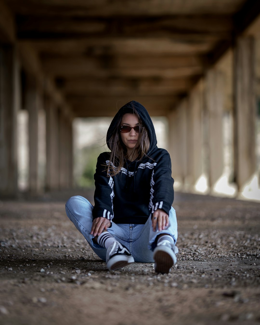woman in black hoodie and blue denim jeans sitting on ground