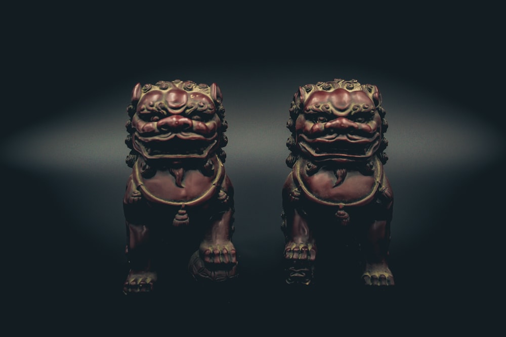 two brown ceramic figurines on black surface