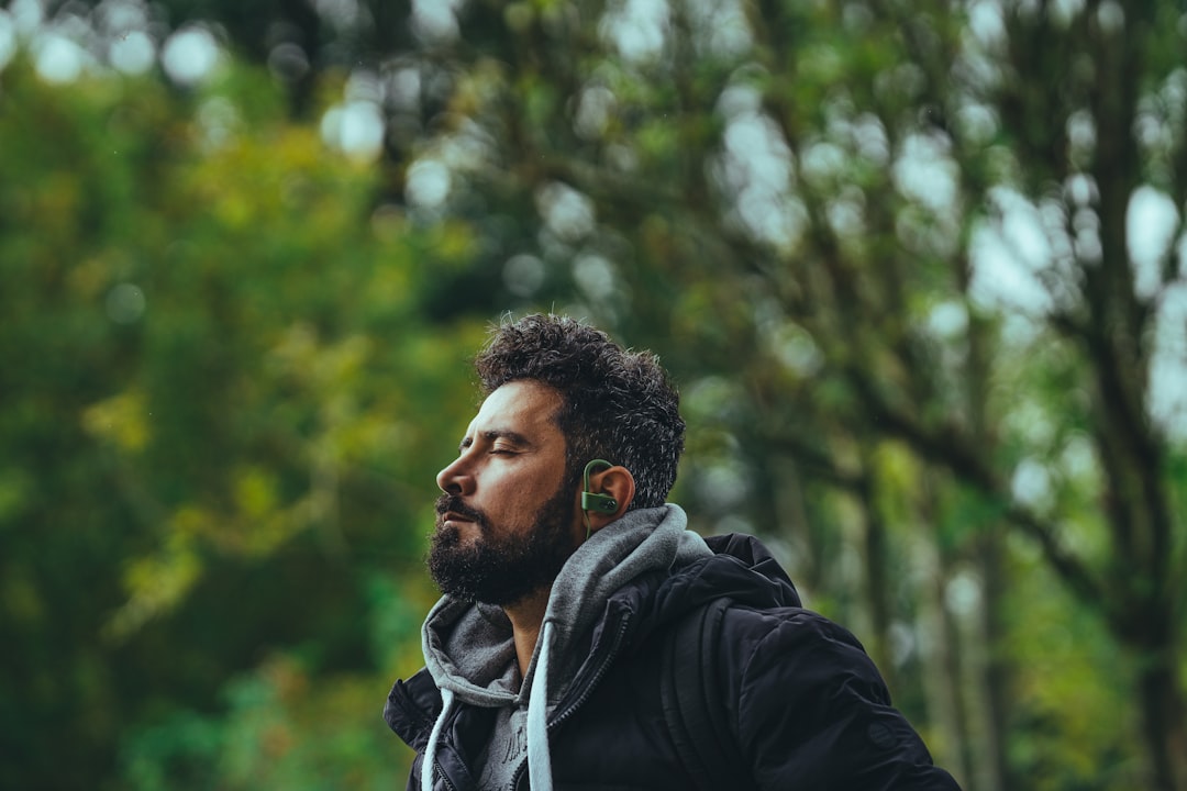 man in black hoodie standing near green trees during daytime