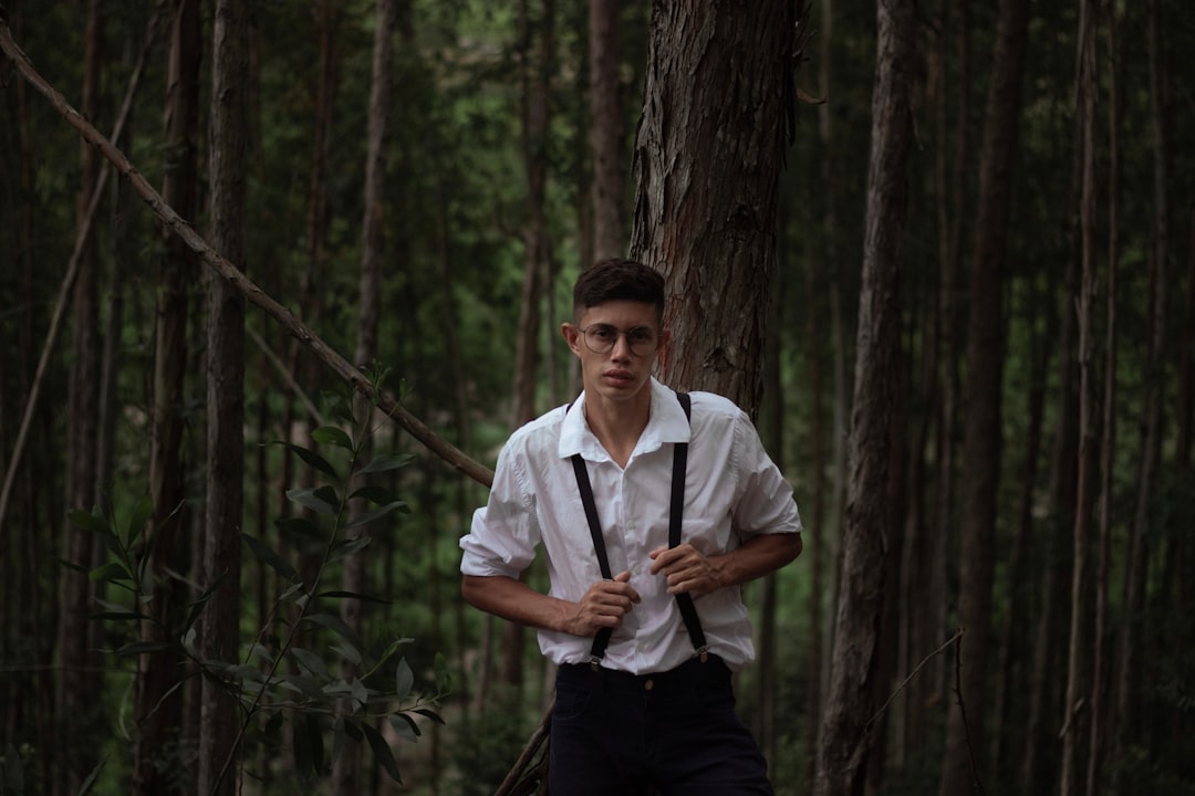 man in white button up shirt and black pants standing in forest during daytime