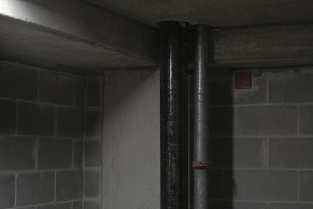 A technician inspecting a sump pump installation in a clean basement.