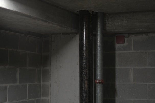 A plumber inspecting a sump pump in a basement.