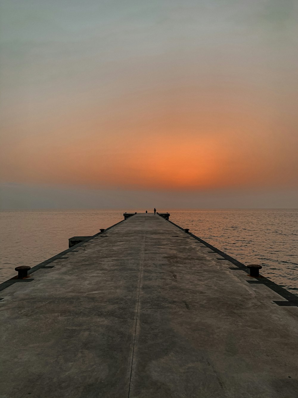 Muelle de hormigón gris en el mar durante la puesta del sol