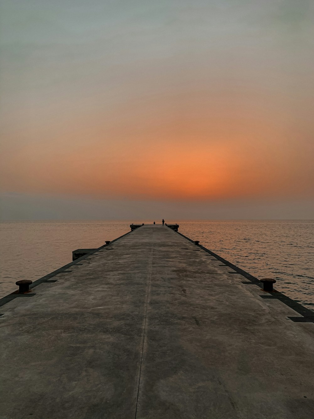 gray concrete dock on sea during sunset