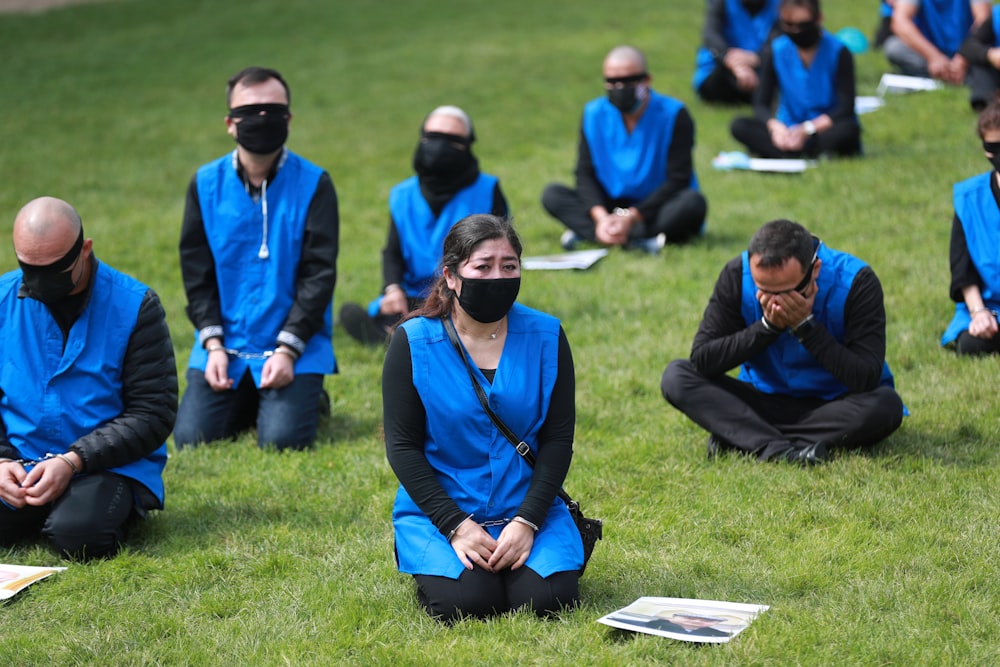 uomo in giacca blu che si siede accanto alla donna in giacca blu sul campo di erba verde durante il giorno