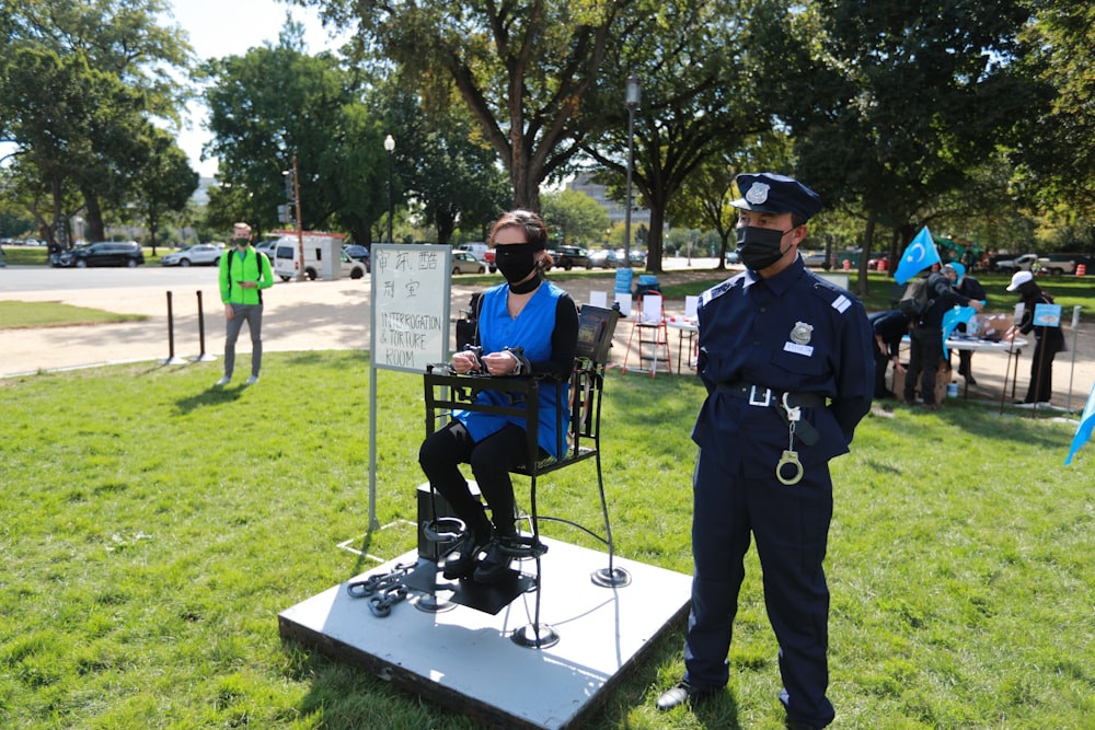 man in blue police uniform standing on green grass field during daytime