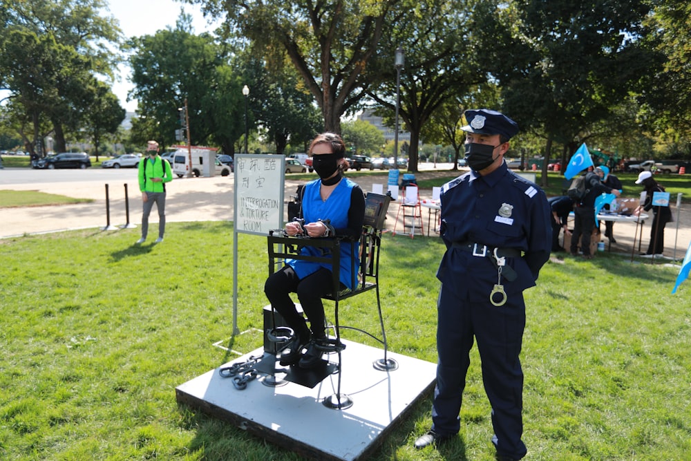 uomo in uniforme blu della polizia in piedi sul campo di erba verde durante il giorno
