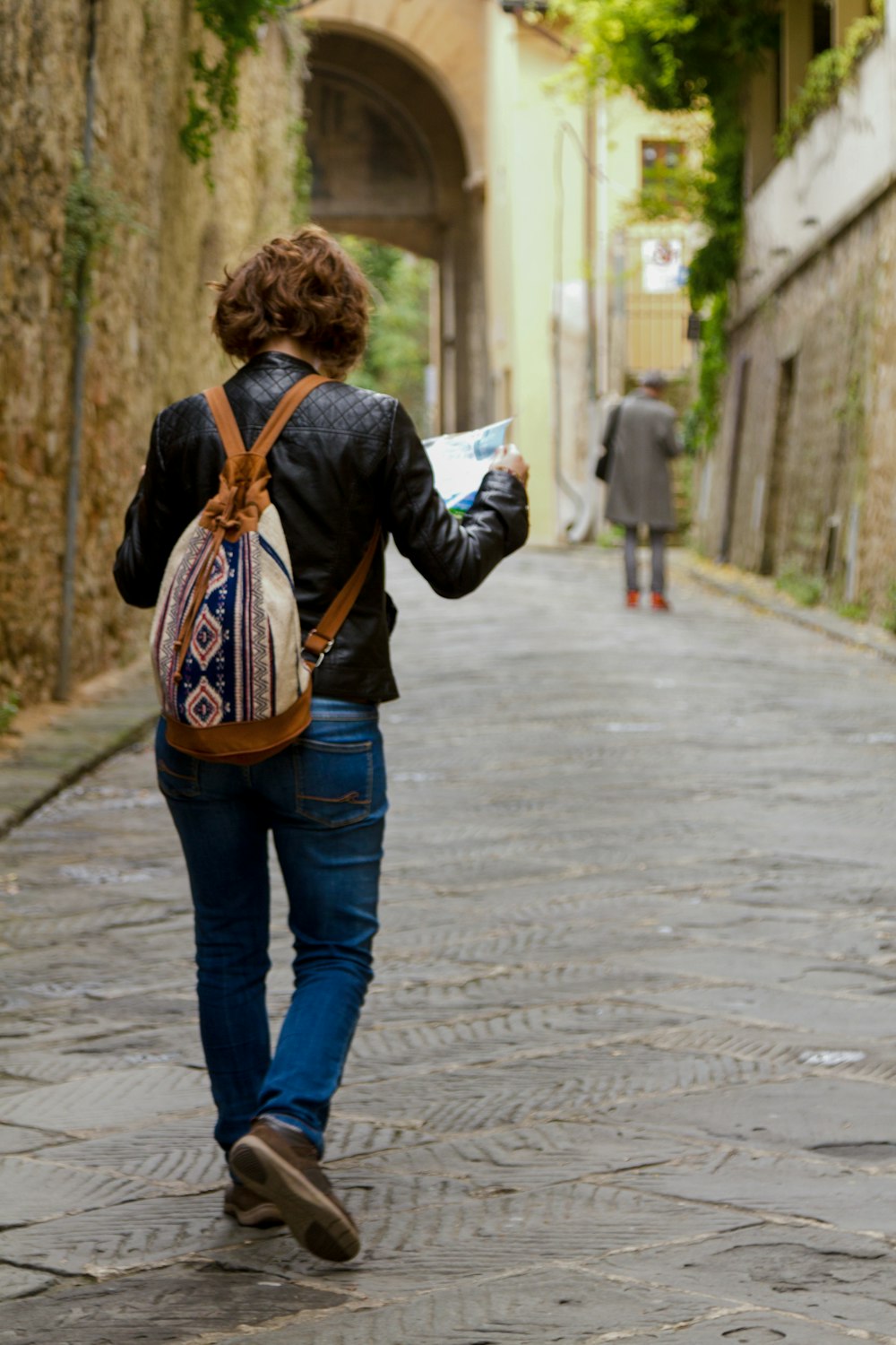 a woman walking down a street with a book in her hand