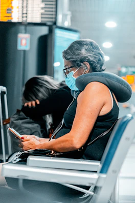 woman in blue tank top wearing white headphones holding smartphone