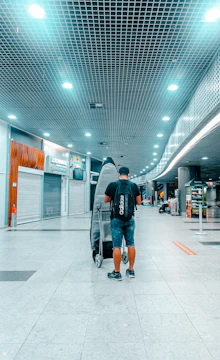 man in black jacket and blue denim jeans walking on white floor tiles