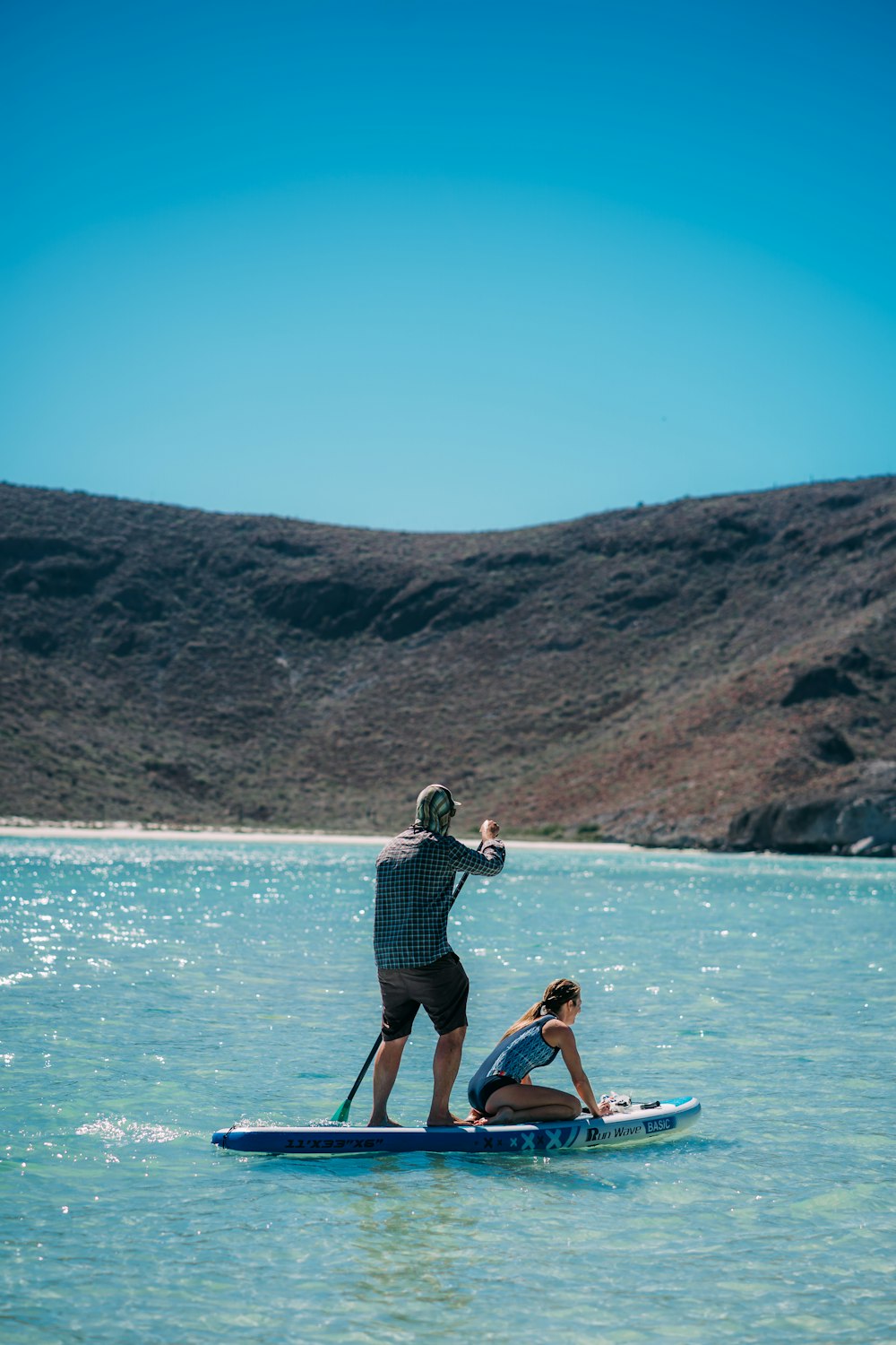 man in black shorts and blue shirt sitting on brown wooden boat on blue sea during