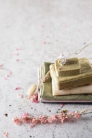 A flat lay of various soap bars with small dried flowers and leaves, evoking natural ingredients and care.