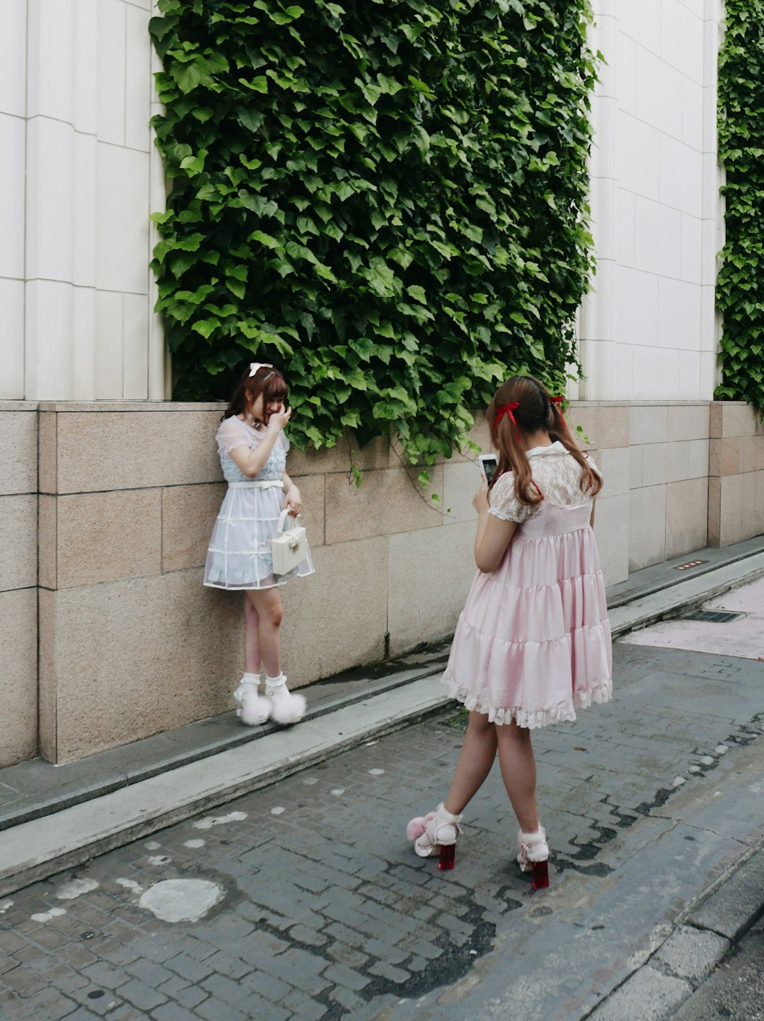 2 girls standing on sidewalk during daytime