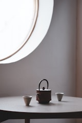 A minimalist tea set arranged on a sleek wooden table with soft natural light highlighting the smooth ceramic surfaces.
