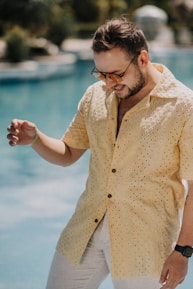 A happy man wearing a luvars fashion shirt, smiling on a sunny day outdoors.