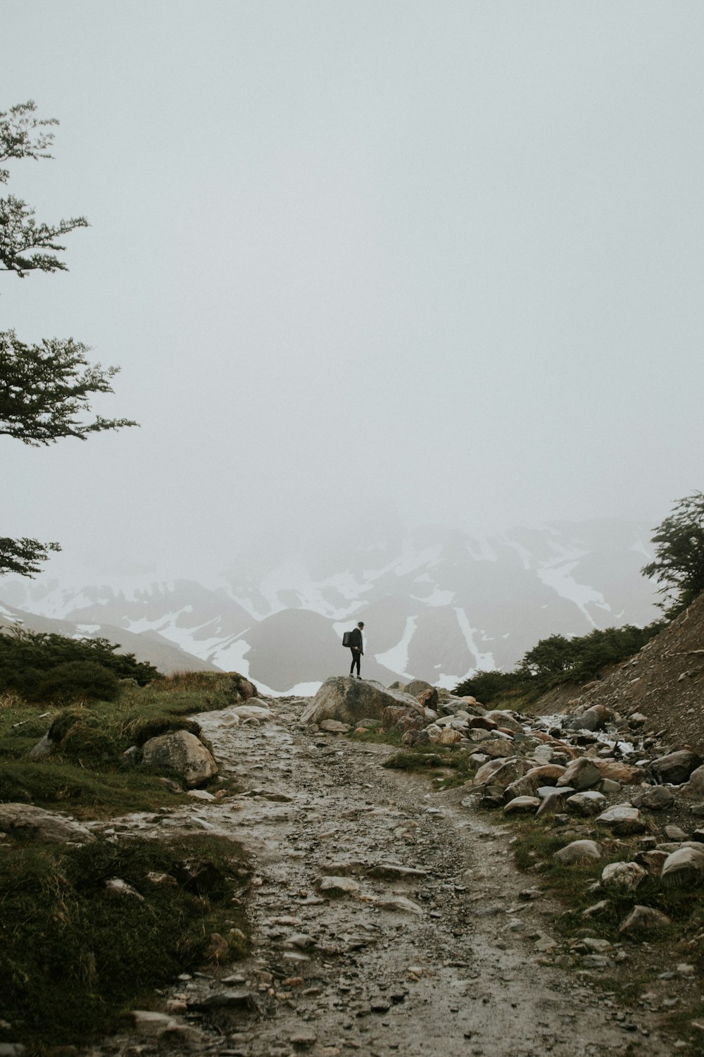 Persona in piedi sulla collina rocciosa durante il giorno