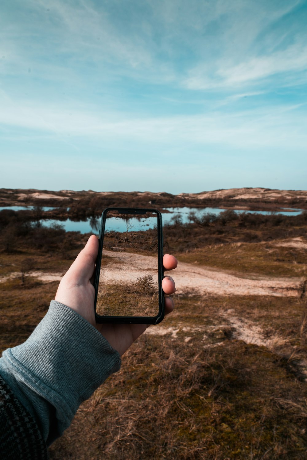 person holding black smartphone taking photo of brown field during daytime
