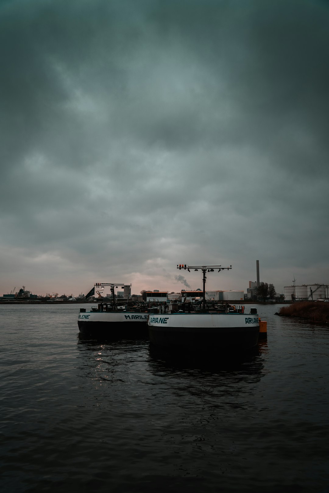 white and blue boat on water under gray sky