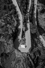 A winding mountain road viewed from inside a van’s windshield.
