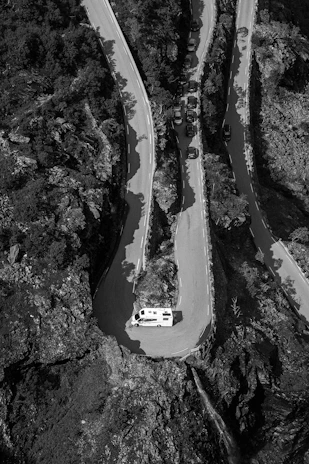 Wide shot of the camper van driving along a winding mountain road with expansive views.