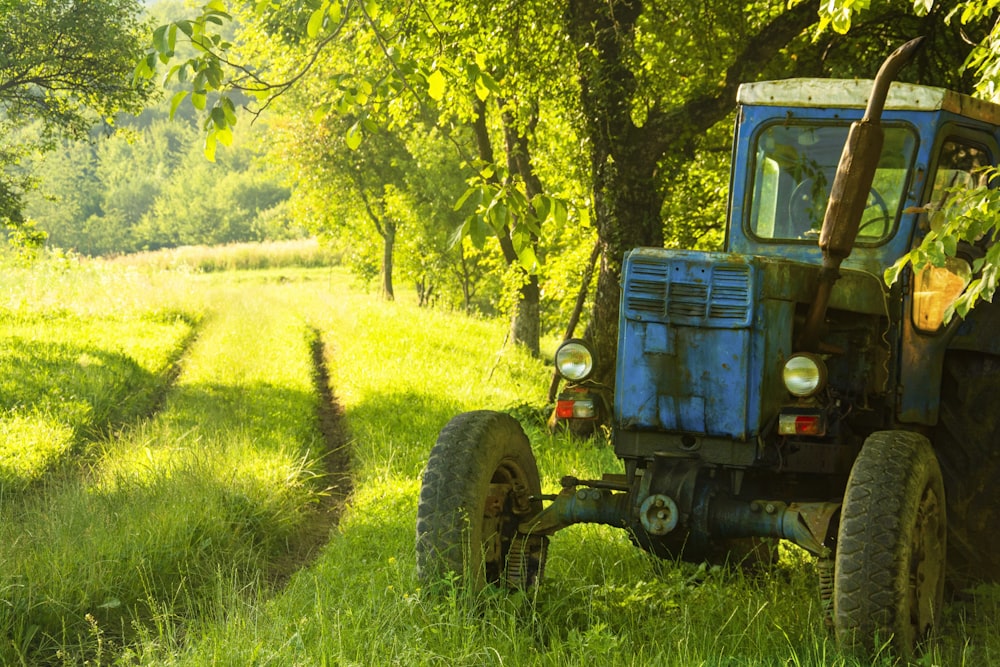 tracteur bleu sur un champ d’herbe verte pendant la journée