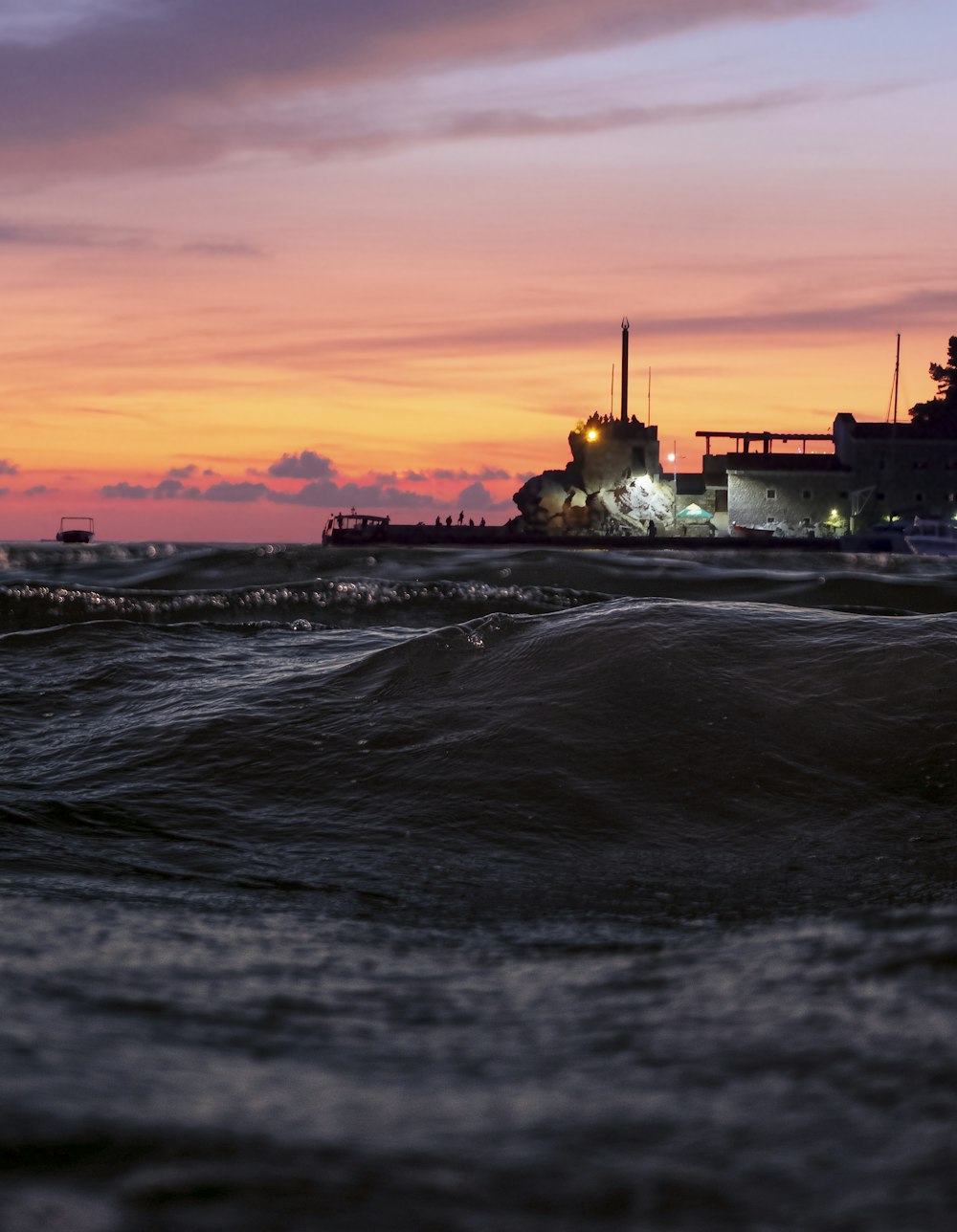 silhouette of building near body of water during sunset