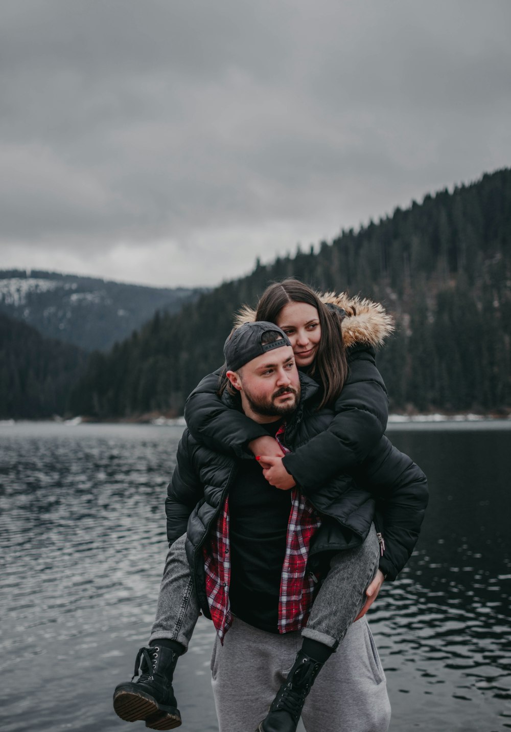 woman in black jacket standing near lake during daytime