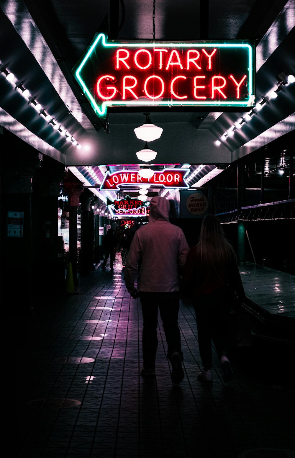 man in gray jacket walking on sidewalk during night time